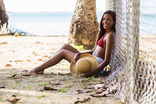 Cheerful teen girl sitting at the beach Happy teenage girl with a hat while at the beach located in Luquillo, Puerto Rico. hot puerto rican woman stock pictures, royalty-free photos & images