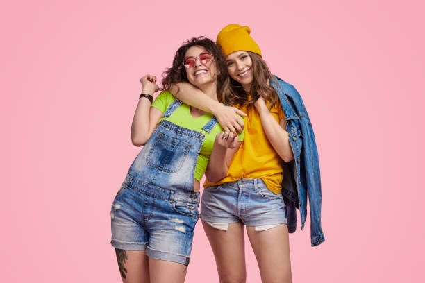 cheerful teenager hugging best friend - friends color background imagens e fotografias de stock