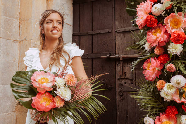 Cheerful wedding bride posing with a bouquet of flowers outdoors stock photo