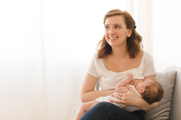 Cheerful woman breastfeeding child stock photo
