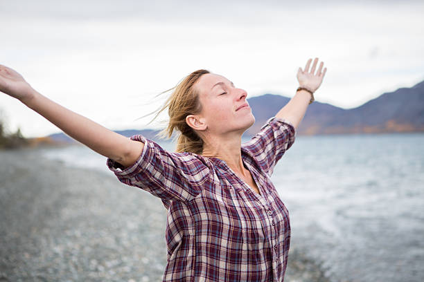 Photo of Cheerful woman by the lake arms outstretched for positive emotion