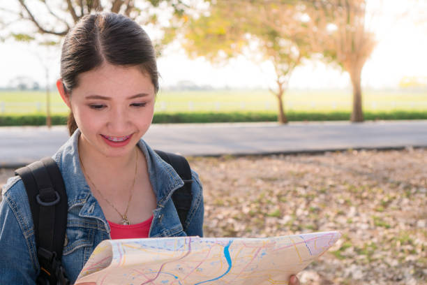 Cheerful woman Read the road map. She looks happy with the trip and searching direction on location map while traveling abroad in summer. Travel concept. stock photo