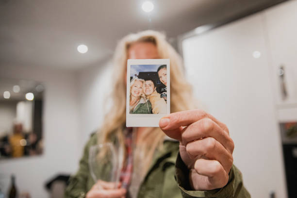 Cheerful Woman Showing Instant Selfie A front-view shot of a cheerful woman holding an instant print camera image in front of her face. holding photos stock pictures, royalty-free photos & images
