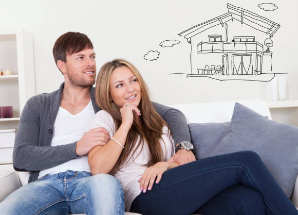 Cheerful young couple dreaming about the future Cheerful young couple dreaming about the future sitting at couch model house stock pictures, royalty-free photos & images