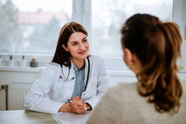 Cheerful young doctor listening to a patient in the office. Cheerful young doctor listening to a patient in the office. woman talking to doctor stock pictures, royalty-free photos & images