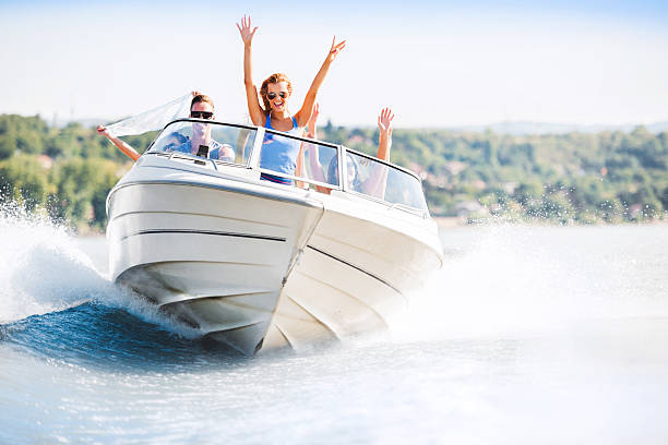 Cheerful young people riding in a speedboat Group of young people with raised hands enjoying in a speedboat ride.    lake stock pictures, royalty-free photos & images