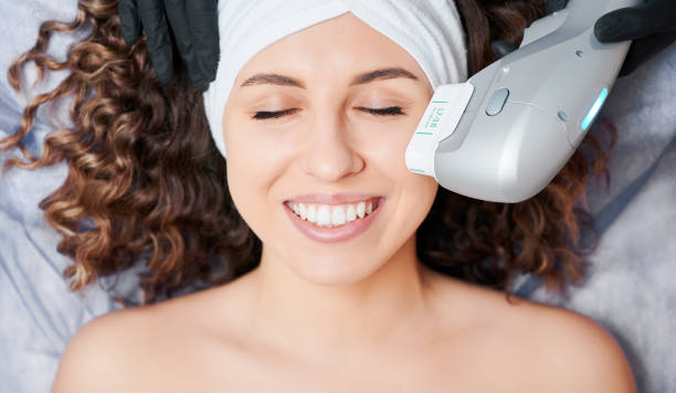 Cheerful young woman having face lifting procedure in clinic. stock photo