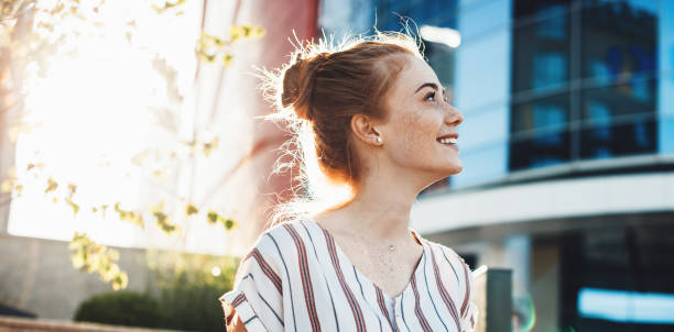 glad ung kvinna med fräknar och rött hår poserar mot solskenet och leende tittar upp - stadler bildbanksfoton och bilder
