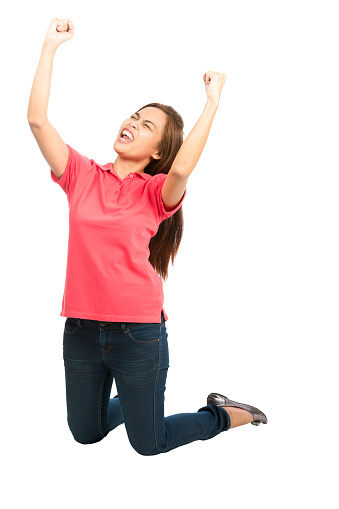 Cute asian woman casual clothes kneeling, arms extended punching air, pumping fists cheering, celebrating favorite sports team goal, touchdown, score, win while looking up and away from the camera