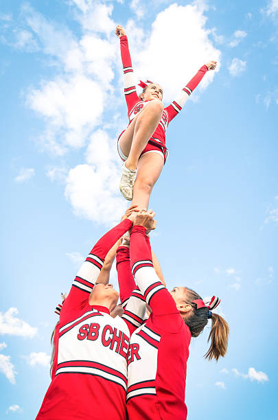 cheerleaders team during competition outdoors - hogeschool rood samen stockfoto's en -beelden