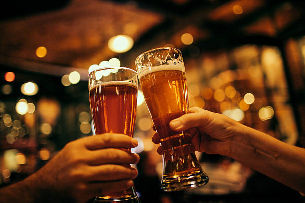 Cheers A couple celebrating cheering with two glasses of beer. beer stock pictures, royalty-free photos & images