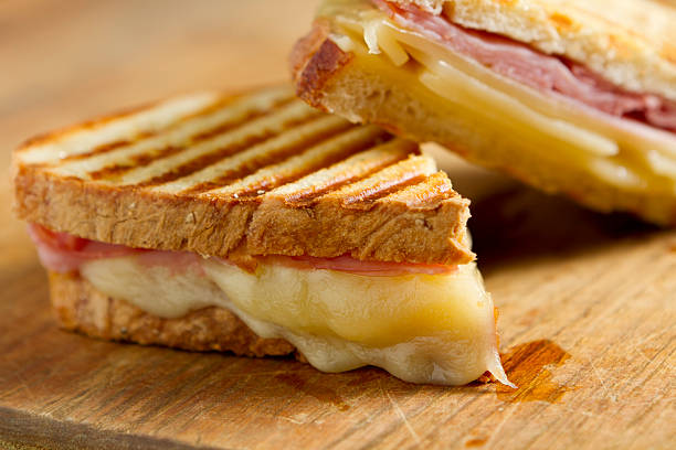 Cheese and ham panini sandwiches on a wooden board stock photo