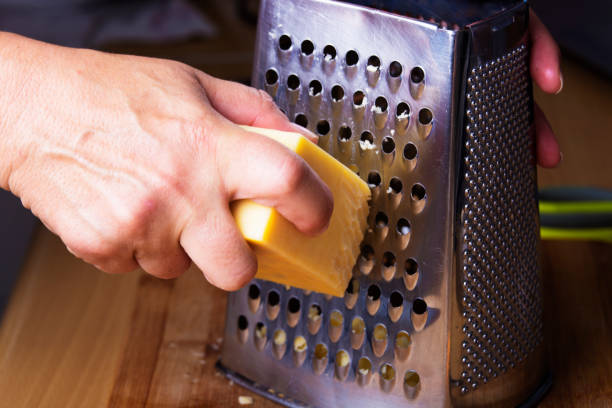 Cheese beeing grated in the kitchen Cheese beeing grated in the kitchen with a cheese grater grater utensil stock pictures, royalty-free photos & images