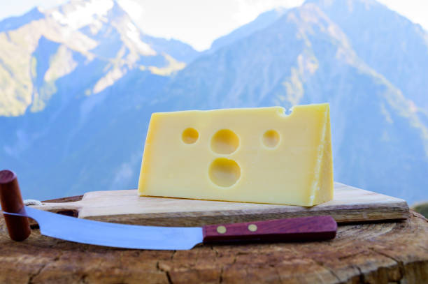 Cheese collection, French emmental de savoie cheese with round holes served outdoor in Savoy region, with Alpine mountains peaks on background stock photo