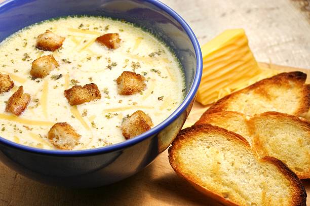 Cheese soup in blue ceramic bowl with toasted bread stock photo
