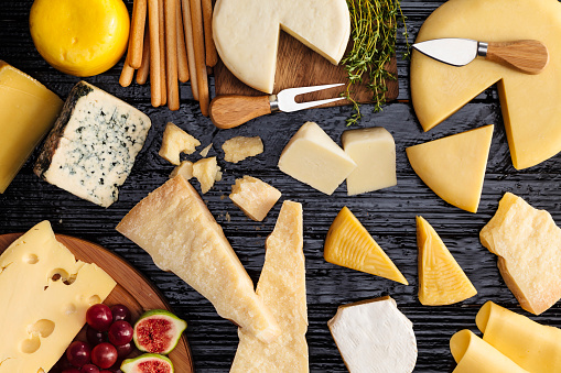 Top view of a dark table filled with a wide variety of cheeses.
