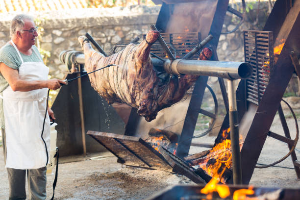 chef cooking on fire whole bull carcass - idosos aquecedor imagens e fotografias de stock