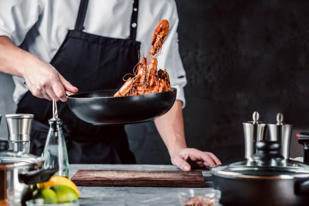 Chef cooking with Tiger prawn on dark background stock photo