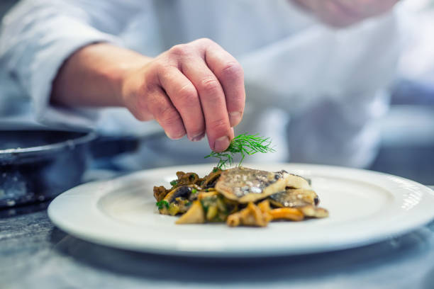 chef-kok in hotel of restaurant keuken koken, alleen handen. bereide vis steak met dille decoratie - chic dineren stockfoto's en -beelden