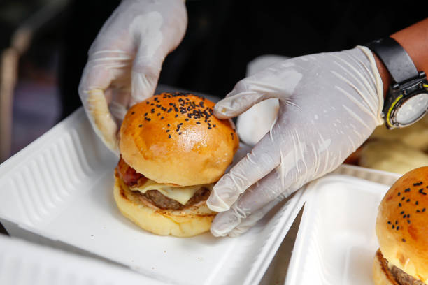 Chef's homemade burger ready to eat Close up shot male chef preparing take out cheeseburger inside a  food truck comfort food stock pictures, royalty-free photos & images