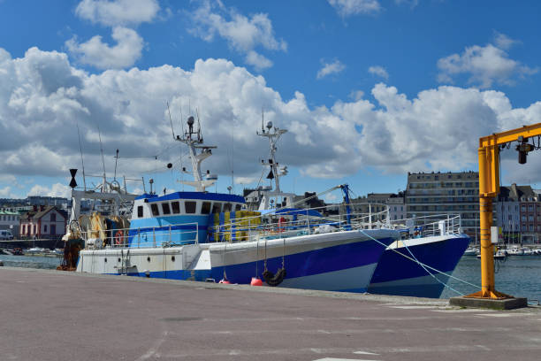 Cherbourg Fishing Trawlers in Spring Two commercial fishing trawlers with lobster traps lashed down moored in the Cherbourg harbor on a beautiful spring day with a nice cloudscape of cumulus clouds in the background manche stock pictures, royalty-free photos & images