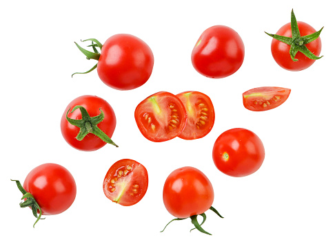 Cherry tomatoes and halves are flying close-up on a white background. Isolated