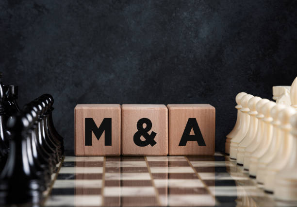 Chessboard with chess pieces and wooden blocks with the word mergers and acquisitions stock photo