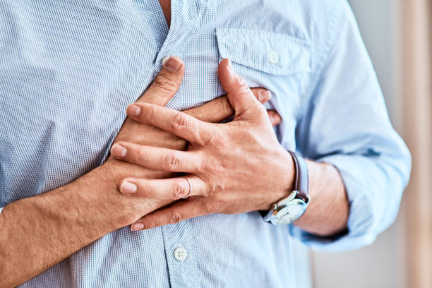 Chest pains are never a good sign Shot of a unrecognizable man holding his chest in discomfort due to pain at home during the day chest pain stock pictures, royalty-free photos & images