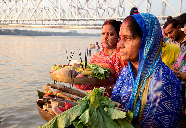 Chhath festival at Jagannath Ghat Kolkata,W.B., India- October 29, 2014: Two women worshiping Sun God at river  Ganges, Jagannath Ghat on the occasion of Chhath Puja festival. chhath stock pictures, royalty-free photos & images