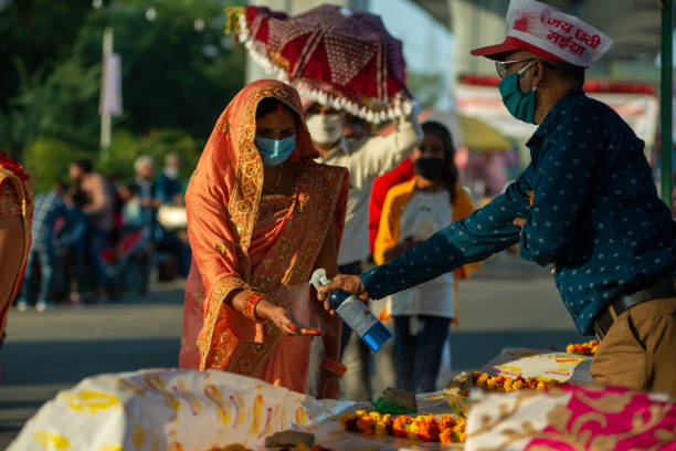 Chhath Pooja Saree clad woman in mask sanitises her hands during festival of 'Chhath Puja'. chhath stock pictures, royalty-free photos & images