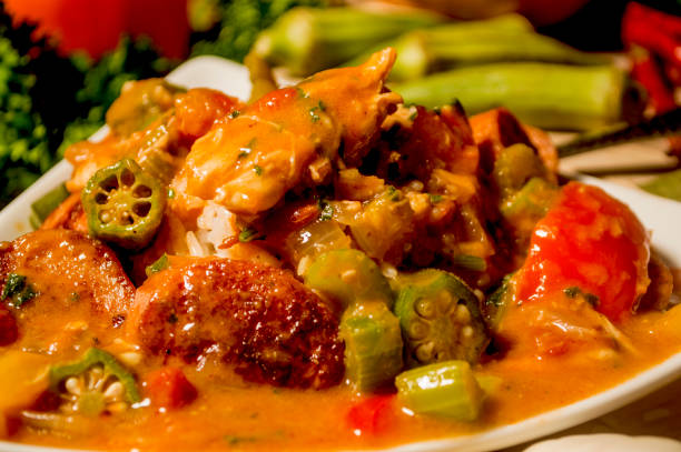 chicken and sausage gumbo fresh made chicken and sausage gumbo served over white rice with fresh vegetables in the background okra photos stock pictures, royalty-free photos & images