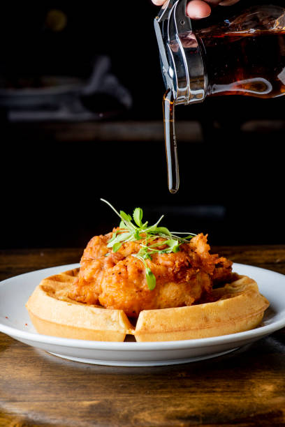 Chicken and waffles. Homemade waffles with crispy southern fried chicken, butter and maple syrup. Classic American breakfast or brunch favorite. Made from scratch waffles served with butter and maple syrup. stock photo