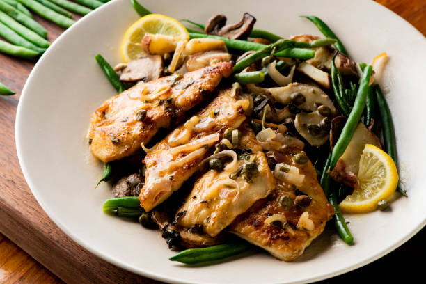 Chicken breast or chicken piccatta, pan seared to a crispy golden brown in brown butter and served with farm fresh organic vegetables: carrots, Brussels sprouts and green beans. Classic American restaurant favorite. stock photo