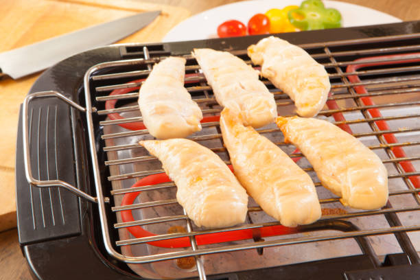 chicken breasts fillet on electric barbecue and grill stock photo
