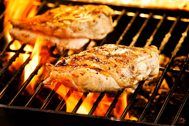 Chicken breasts grilling over an open flame Photograph of two chicken filets on the barbecue chicken meat photos stock pictures, royalty-free photos & images