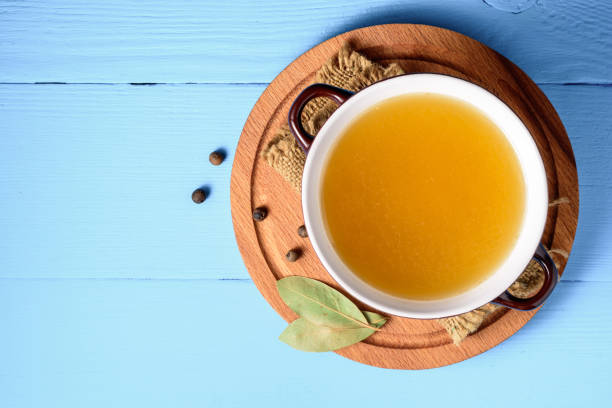 Chicken broth in ceramic bowl on blue wooden background. stock photo