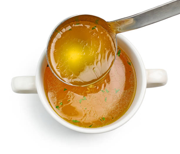 chicken broth pouring into bowl stock photo