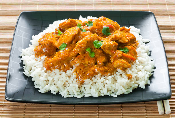 Chicken curry and rice on black plate on bamboo matting stock photo