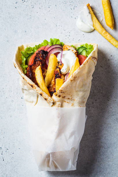 Chicken gyros with vegetables, french fries and tzatziki sauce. Greek food concept. stock photo