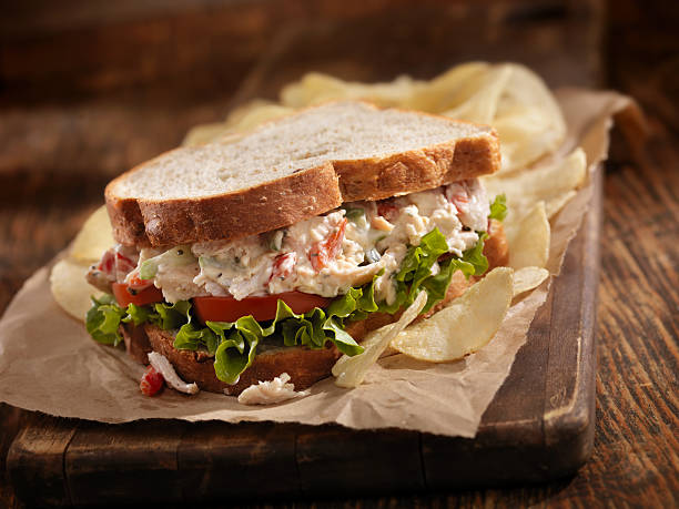 Chicken Salad Sandwich A Creamy Chicken Salad Sandwich with Red Peppers, Cucumber, Lettuce and Tomato on Whole Wheat Bread and Potato Chips on the side- Photographed on Hasselblad H3D2-39mb Camera chicken salad stock pictures, royalty-free photos & images