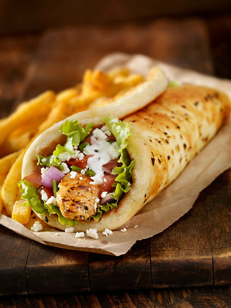 Chicken Souvlaki Wrap Chicken Souvlaki Pita Wrap with Lettuce, Tomatoes, Red Onions, Feta Cheese, Tzatziki Sauce and a Side of french Fries -Photographed on Hasselblad H3D-39mb Camera shawarma stock pictures, royalty-free photos & images
