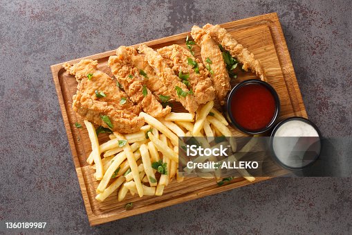 istock Chicken strips with ketchup, mayonnaise and french fries closeup on a old concrete table. Horizontal top view 1360189987