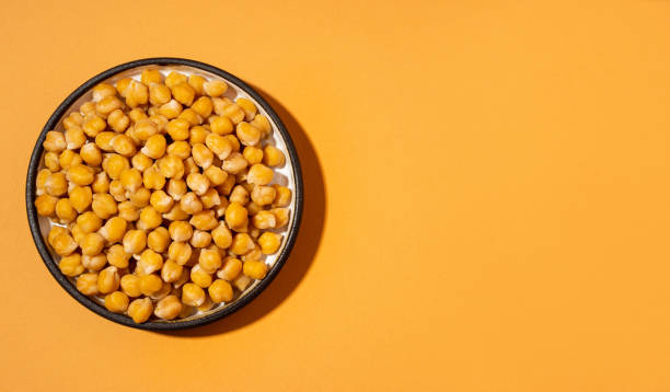 Chickpeas in small yellow ceramic plate bowl isolated on beige orange background.vegetarian dish. style minimalism banner Chickpeas in small brown ceramic plate bowl isolated on beige orange background.vegetarian dish. style minimalism banner. on bowl close up - concept healthy vegan diet protein organic food dish pea protein powder stock pictures, royalty-free photos & images