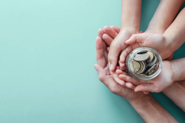 child and parent hands holding money jar, donation, saving, family finance plan concept child and parent hands holding money jar, donation, saving, family finance plan concept family money stock pictures, royalty-free photos & images