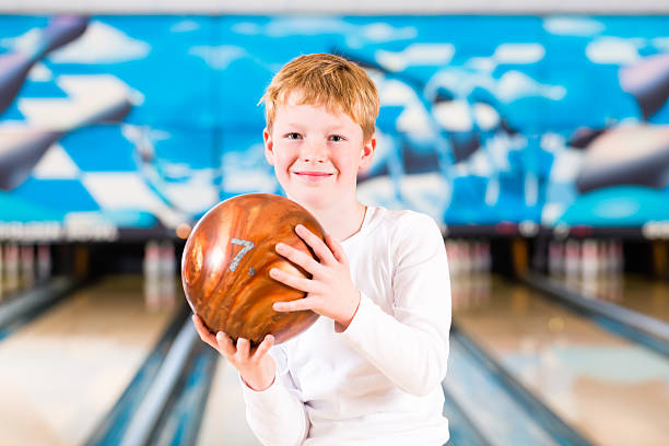 Child bowling with ball in alley stock photo