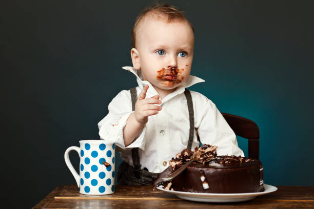 A child covered in chocolate cake on his face  His first birthday cake proudly humorous happy birthday images stock pictures, royalty-free photos & images