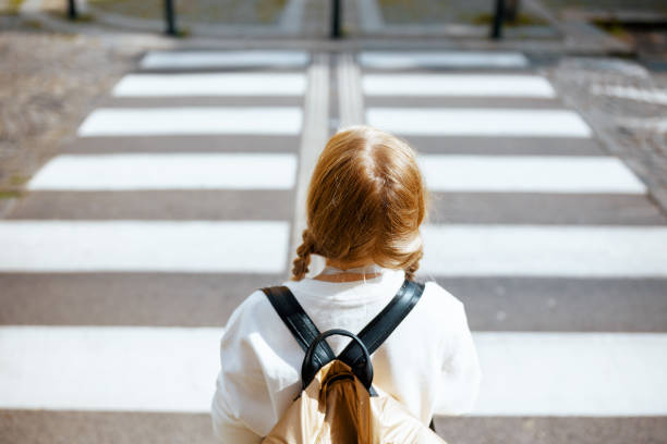 child crossing crosswalk and going to school outdoors in city stock photo