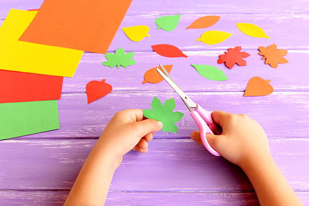 Child cuts out colored paper leaf stock photo