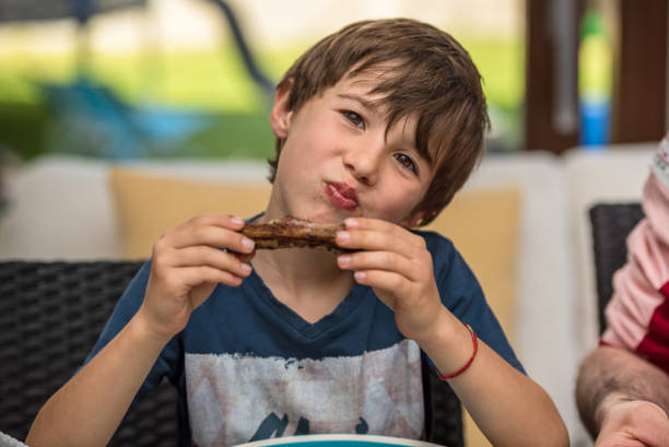 Child eating of pork ribs Child at the table eats with his hands cut of meat stock pictures, royalty-free photos & images
