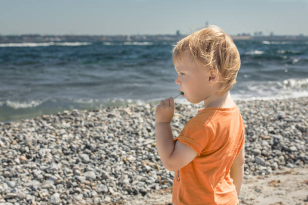 Child eats lollipop is on seashore stock photo